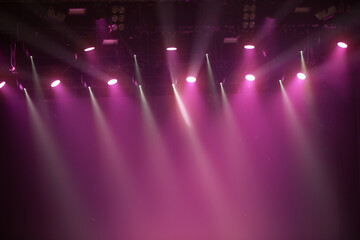 A stage with lights shining on it. The lights are pink. There are many lights