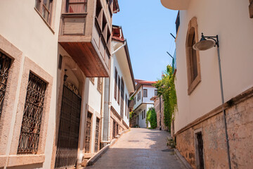 A narrow old street with a stone wall on the side. The street is lined with houses and has a stone path.