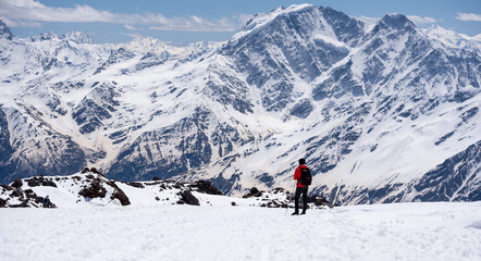 A man walking on the snowy mountains with snowshoes on. Climbing the icy mountains