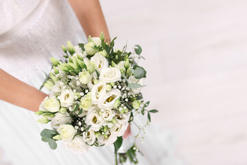 Bride with beautiful wedding bouquet on light background, closeup. Space for text