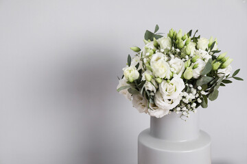 Wedding bouquet of beautiful flowers in vase against grey wall, closeup. Space for text