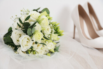 Beautiful wedding bouquet, veil and bridal shoes on light background, closeup