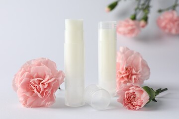 LIp balms and eustoma flowers on white background, closeup