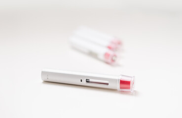 A clean an aseptic white pen injector with a red tip for biological treatments such as Adalimumab, Etanercept or epinephrine. The background is a white light, aseptic, clean, white and well lit.