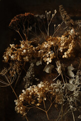 Detailed closeup view of dried hydrangea flowers, eucalyptus herbs. Tiny fine blossom arrangement. Blurred dark moody background. Neutral floral textures, selective photo. Beauty in nature. Vertical