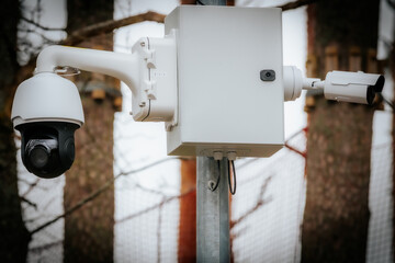 A close-up of a modern surveillance camera system mounted on a metal pole, featuring a dome camera...
