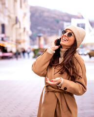 Obraz premium Caucasian woman walking in the city street and using a cellphone