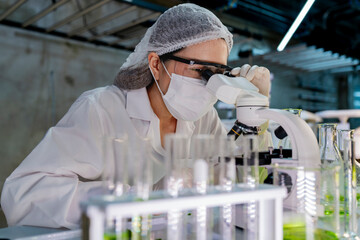 A researcher in a sterile lab conducts a scientific experiment using a microscope and test tubes....
