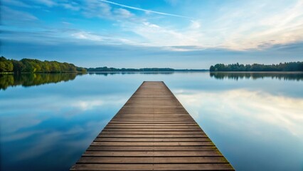 Fototapeta premium a wooden pier extending into a tranquil lake with calm water reflecting the clear sky