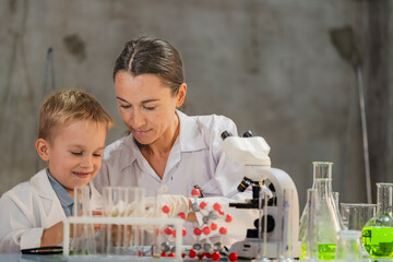 A female scientist teaching a young boy about science in a modern lab. Inspiring the next generation through STEM education, scientific curiosity, and hands on experiments in chemistry and biology.