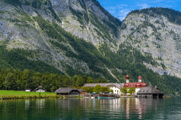 Naklejka premium Beautiful view of St. Bartholomae pilgrimage church at lakeside of Konigssee Lake with Bavarian alps in background in Berchstegaden national park, on a sunny summer day, Schoenau, Bavaria, Germany