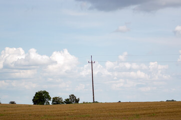 Krajobraz drewniany słup energetyczny w polu na tle chmur na niebie. © Monika