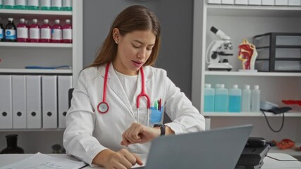 Young caucasian woman doctor in uniform checking time on wrist watch at clinic, focused on punctuality and professionalism
