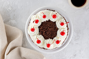 Black forest cake, Schwarzwald pie with cup of tea on a table. Cake with dark chocolate, whipped cream and cherry. Top view.