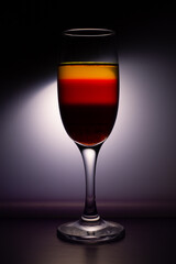 A glass of champagne with colorful liquid on grey background