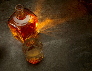 Bottle and crystal glass of whiskey on a stone table.