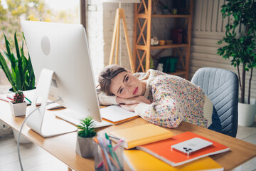 Young woman resting at a stylish workstation in a cozy living space filled with natural light,...