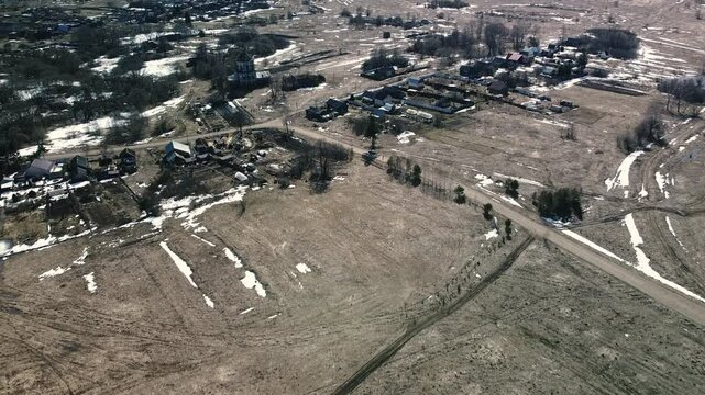The village is surrounded by fields with faded grass after snowmelt