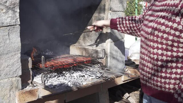 arm of woman in unrecognisable jumper twirling meat on barbecue