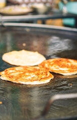 Golden-brown parathas sizzling on a hot griddle, frying in oil as they cook to perfection in a street food setting.