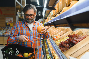 Positive elderly man buying seasonal vegetables in local market
