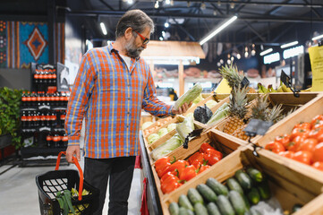 Positive elderly man buying seasonal vegetables in local market