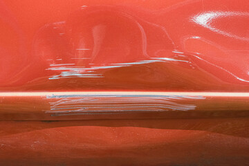 Close up of a red car with multiple visible scratches and paint damage The scratches expose the underlying metal, creating a contrast against the glossy surface. Perfect for automotive damage concepts
