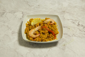 A plate of rice with shrimp and lemon slices