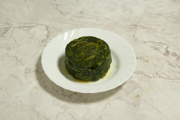 A small green food item sits on a white plate