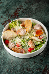 Fresh salad bowl featuring crisp romaine lettuce, cherry tomatoes, grilled chicken, croutons, and a soft-boiled egg, topped with grated cheese on a textured background.