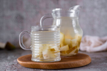 Homemade pear compote in a glass mug and pear compote in a beautiful decanter on a gray background. Close-up