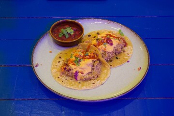 Two tacos with a side of salsa and sour cream