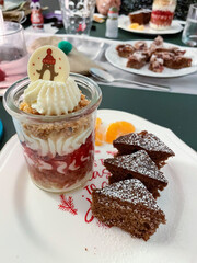 Dessert im Gläschen mit Sahne, Beerenmousse und Hafercrunch, auf einem Teller mit Gewürzkuchen in Tannenbaum Form serviert