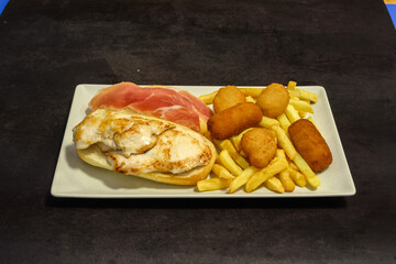 A plate of food with a sandwich, chicken, and french fries