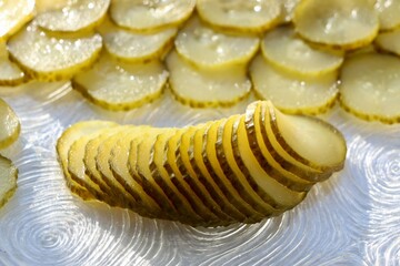 Close up of pickled cucumber sliced ​​into thin slices on a plate. Pickled food