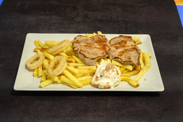 A plate of food with meat, fries, and a sauce