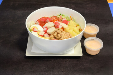 A bowl of salad with a white plate and a napkin