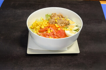A bowl of salad with a variety of vegetables including carrots, tomatoes