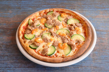 A pizza with shrimp and cucumbers on top