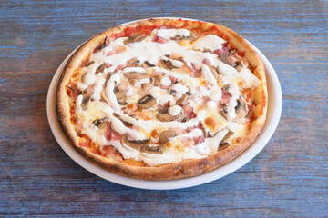 A mushroom and ham pizza is sitting on a white plate