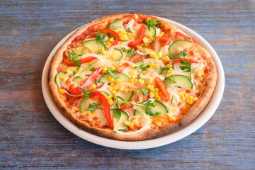 A pizza with vegetables on it is sitting on a white plate