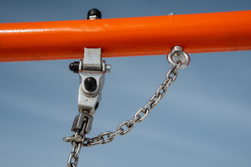 A detailed closeup view featuring a sturdy metal hook and robust chain mounted on a vibrant orange...