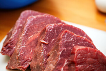 selection of fresh beef steaks neatly arranged on a wooden kitchen table, ready for cooking. Perfect for culinary, food preparation, and grilling themes