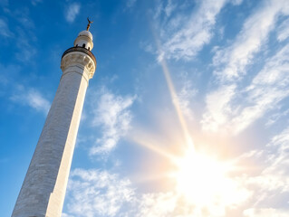Obraz premium Majestic monument under a bright sun, clear blue sky, puffy clouds; perfect for travel brochures or historical site advertising