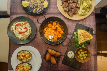 A table with a variety of food, including shrimp, potatoes, and avocados
