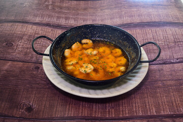 A bowl of shrimp soup is on a wooden table
