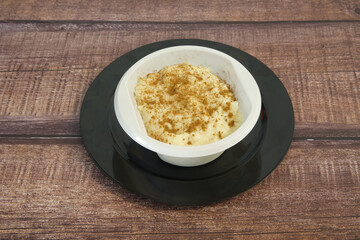 A white bowl of food with brown crumbs on top