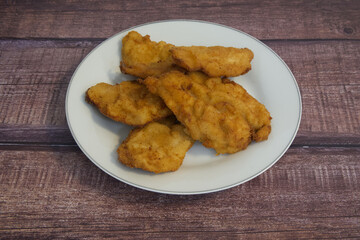 A plate of fried chicken pieces on a wooden table