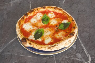 A pizza with a basil leaf on top sits on a blue plate