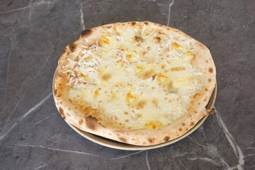 A pizza with cheese on it sits on a plate